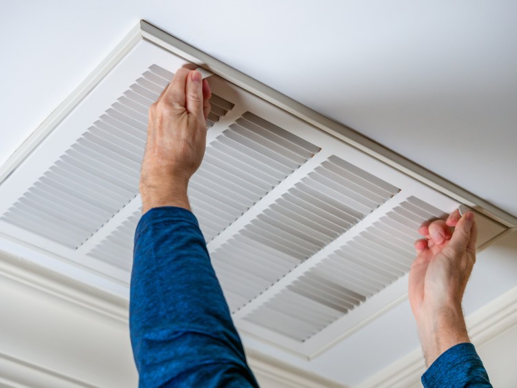 Man opening ceiling of ducted air conditioning